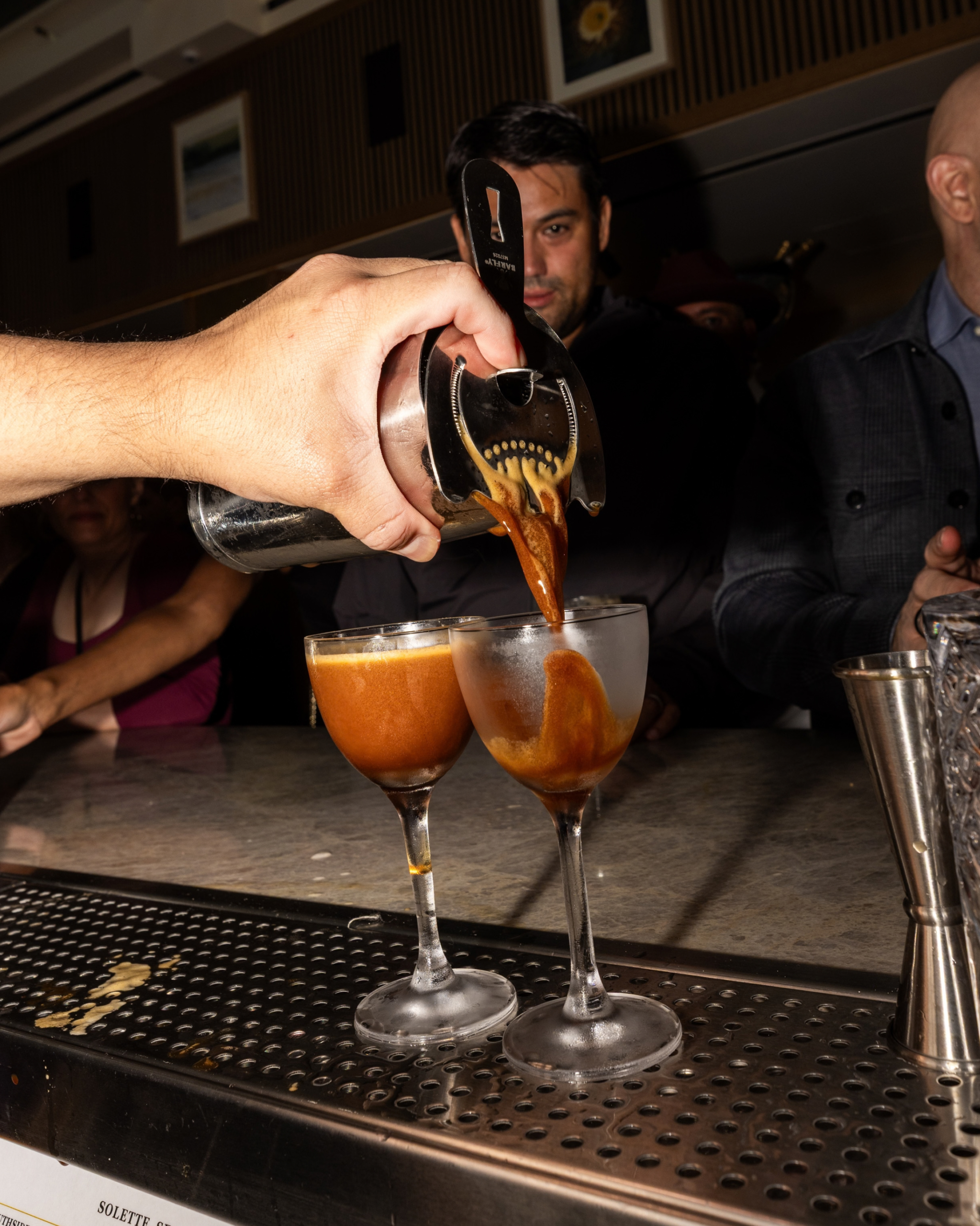 Bartender inside Solette Seattle pouring two espresso martinis at bar