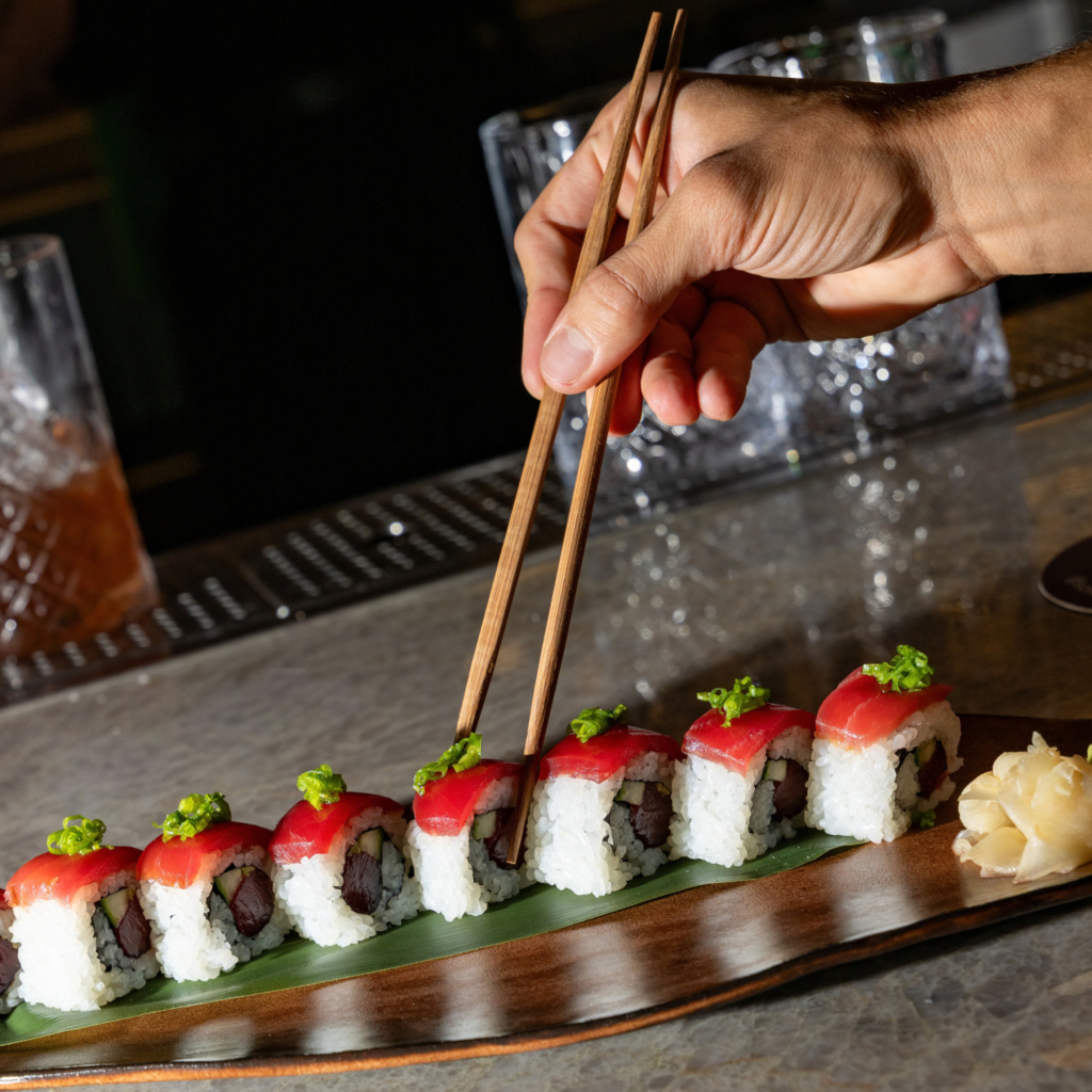 man grabbing sushi with chop sticks